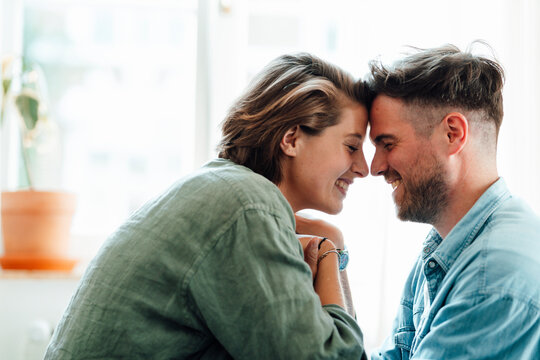 Happy man and woman touching foreheads at home