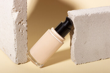 Foundation, concealer on a background of concrete geometric shapes. Face corrector on beige...