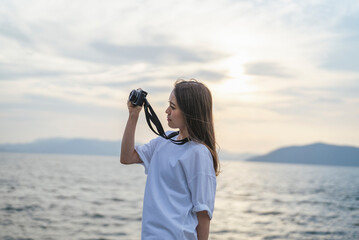 夕暮れの海で写真を撮るカメラ女子