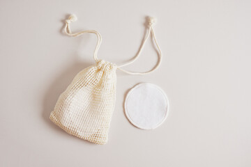 fabric pads for cleansing the skin from makeup and a mesh bag for storing them on a beige background