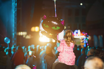 Girl with a ball on daddy's shoulders at a concert