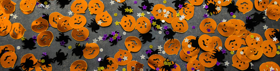 Banner with Halloween background: confetti in the shape of orange pumpkins, black spiders and...