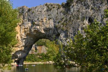 Fototapeta na wymiar Le Pont-d'Arc sur l'Ardèche et ses canoës à Vallon-Pont-d'Arc (07150), département de l'Ardèche en région Auvergne-Rhône-Alpes, France