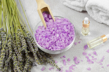 Fototapeta na wymiar Light purple sea salt and lavender bouquet against the background of essential oils and bath accessories. Spa composition