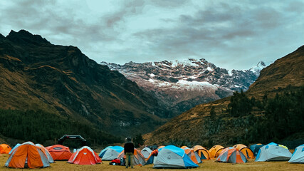 Campamento en la montaña con nevados y cielo dorado