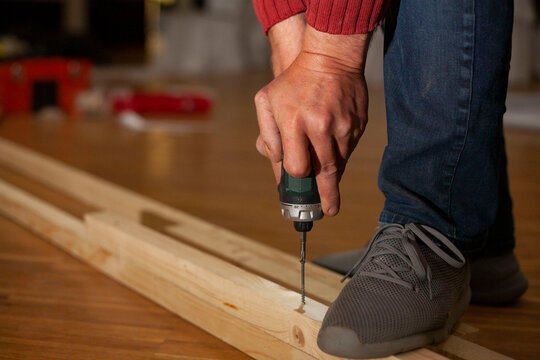 A man works as a screwdriver. Work with an electric tool. Tightening the screw with an electric screwdriver. Men's work.A man without a finger works with an electric drill