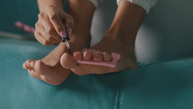 Crop woman doing pedicure on sofa