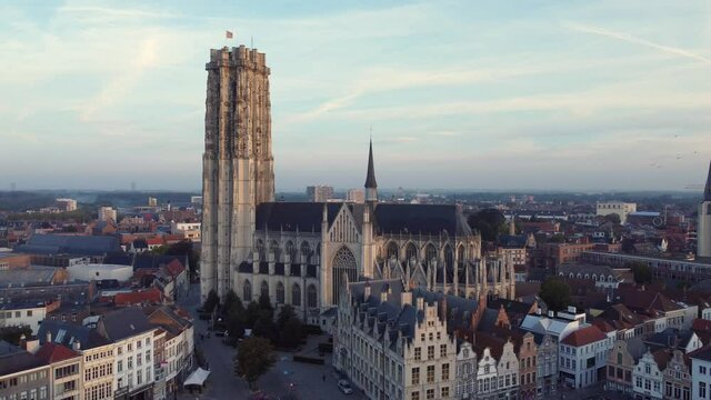 Aerial static shot of birds flying in front of drone by Mechelen Saint Rumbold's Cathedral Sint Rombouts toren in a lovely morning light