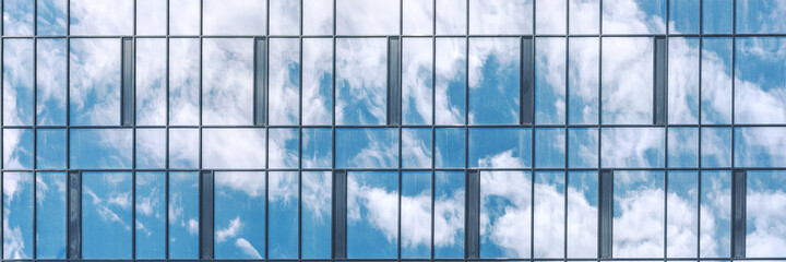 new city building reflects blue sky and fluffy white clouds