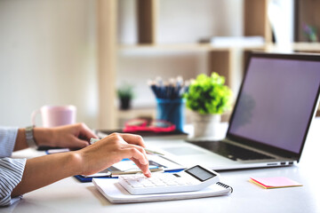 businessman or accountant who are using a calculator to calculate business data Accounting documents and laptop computer at the office business idea