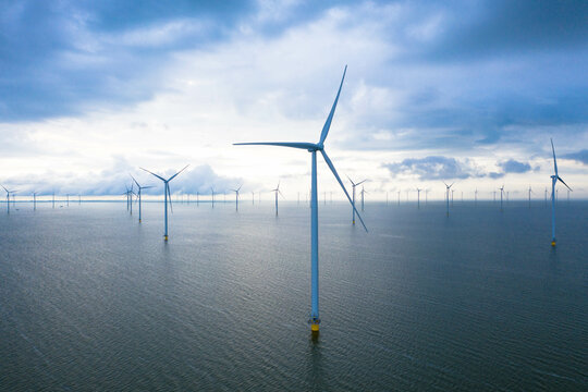 Aerial view, Enormous windmills stand in the sea along a dutch sea. Fryslân wind farm, the largest inland wind farm in the world. Friesland, Ijsselmeer, Breezanddijk, Netherlands