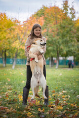 Young beautiful blonde girl is played with a dog in the park.