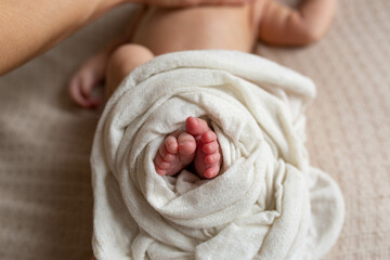 a small leg of the newborn in a white scarf. soft focus