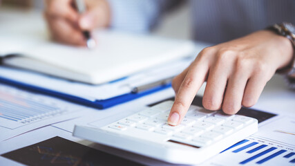 Fototapeta premium business woman or accountant who are using a calculator to calculate business data Accounting documents and laptop computer at the office business idea