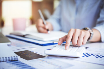business woman or accountant who are using a calculator to calculate business data Accounting documents and laptop computer at the office business idea