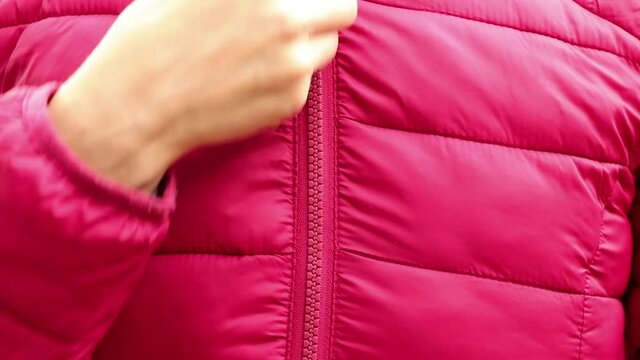 female hand zipper on red winter warm jacket, zipper on clothes, dress up