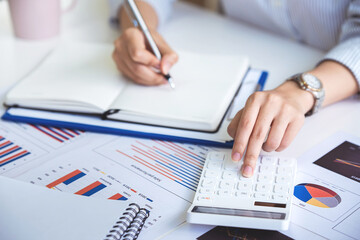 business woman or accountant who are using a calculator to calculate business data Accounting documents and laptop computer at the office business idea