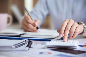 Fototapeta premium business woman or accountant who are using a calculator to calculate business data Accounting documents and laptop computer at the office business idea