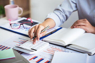 business woman or accountant who are using a calculator to calculate business data Accounting documents and laptop computer at the office business idea