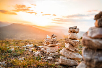 A stone stack with balanced stones on a blurry background of mountains at sunset