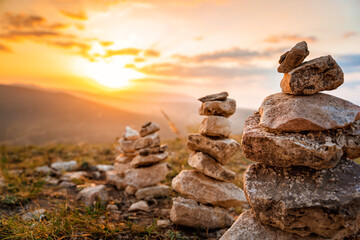 A stone stack with balanced stones on a blurry background of mountains at sunset
