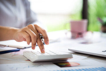 business woman or accountant who are using a calculator to calculate business data Accounting documents and laptop computer at the office business idea