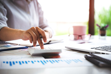 business woman or accountant who are using a calculator to calculate business data Accounting documents and laptop computer at the office business idea