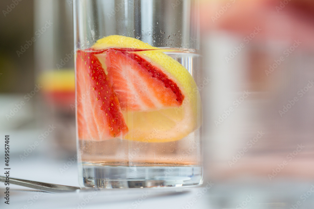 Poster closeup shot of a cocktail with strawberries and lemon in the glass