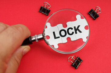 A man looks through a magnifying glass at puzzles with the inscription - LOCK
