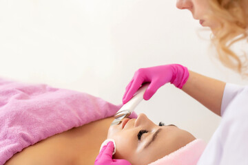 The cosmetologist makes the procedure ultrasonic face peeling of the facial skin of a beautiful,...