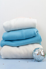 stack of cotton wool sweaters with disco ball isolated on white and light blue background
