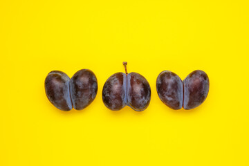 Three ugly plum of shaped heart on yellow background. Ugly vegetables and fruits are suitable for...