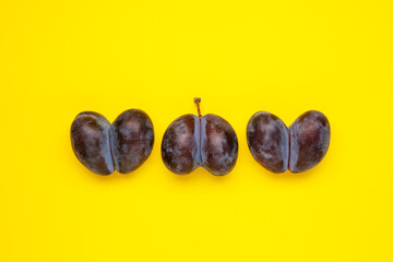 Three ugly plum of shaped heart on yellow background. Ugly vegetables and fruits are suitable for food. Concept - Reduction of organic food waste