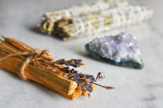A close up image of a smudge sticks with dried lavender and amethyst crystals. 
