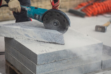 Process of cutting, sawing and grinding granite cement tile slab with cutting machine, worker with circular saw during new walkway asphalt pavement works, worker cuts ceramic concrete tile