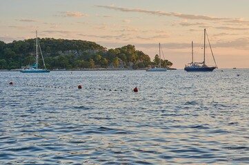 Sailing boats anchoring next to a small island during sunset.