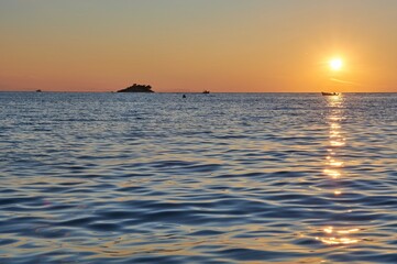 Small boat driving towards the sunset.