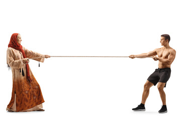Full length profile shot of a young woman wearing a hijab and a strong young man pulling a rope