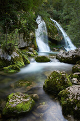 Long exposure of a beautiful waterfall in Slovenia. Small stream with mossy rocks and a beautiful waterfall in the background..