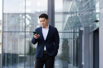 Successful Asian boss corresponded on the phone serious in a business suit