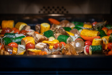 à l'intérieur d'un four, des légumes méditerranéens cuisent sur une plaque de cuisson