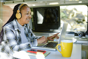 Smiling black traveler working on netbook in van