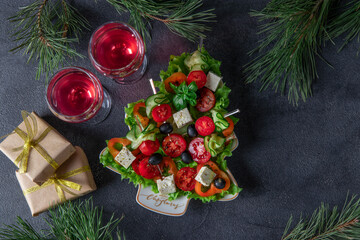 Festive canapes with cucumbers, tomatoes and cheese served in plate as Christmas tree, on dark gray background with two glasses of wine