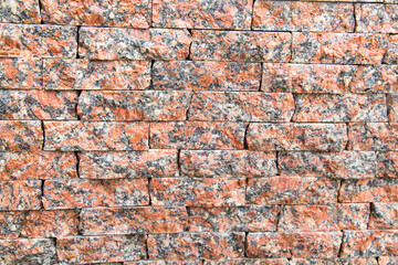 The background of the wall is made of strips of natural granite of Kapustinsky pink color with a beautiful stone pattern. Backgrounds texture design.