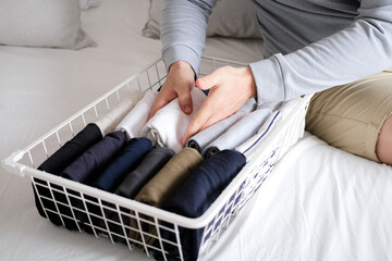 Closeup of hands of an man tidy up things in mesh storage containers. Vertical storage of clothing.