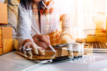 Young woman small business owner online shopping at home. taking note of orders from customers with mobile phones. SME entrepreneur or freelance life style concept.