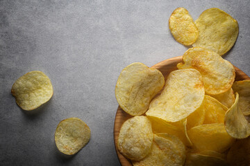 Potato chips in wooden bowl on a concrete background