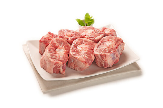 codillo de cerdo fresco crudo cortado sobre plato blanco con servilleta de tela gris aislado fondo blanco