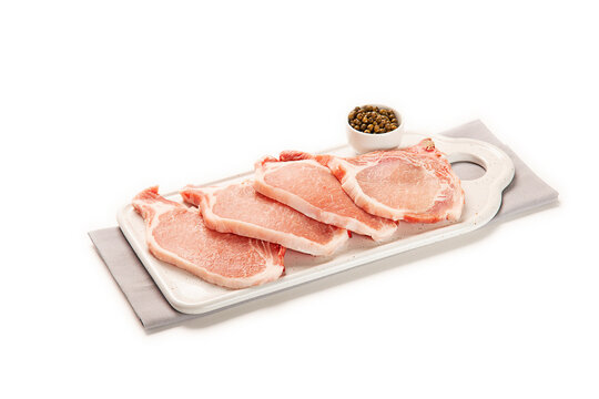 chuletas de lomo de cerdo fresco crudo en una bandeja blanca con especias decorativas y una servilleta de tela gris, aislada fondo blanco