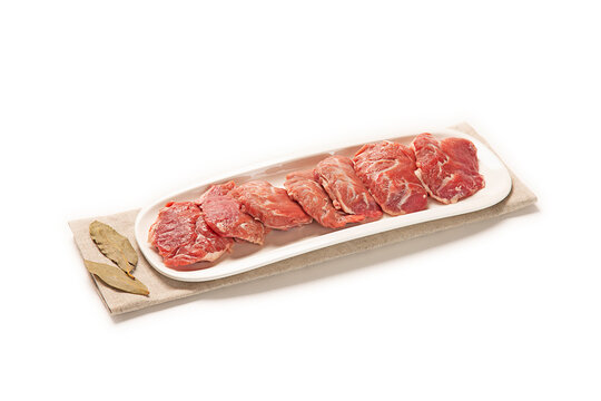 carrilleras de cerdo fresca cruda en plato blanco sobre servilleta de tela con laurel seco aislado fondo blanco